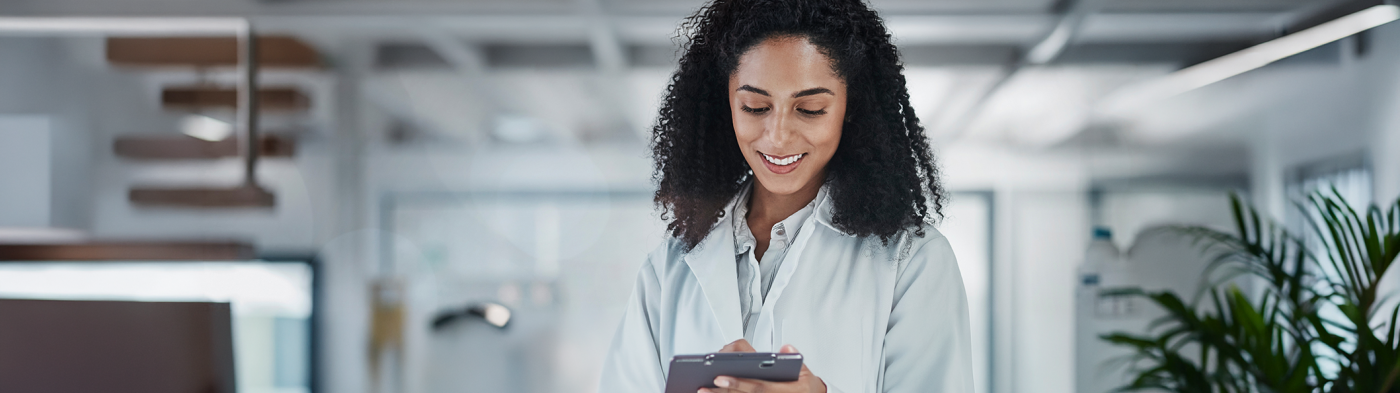 Woman with curls in a white coat looks at tablet
